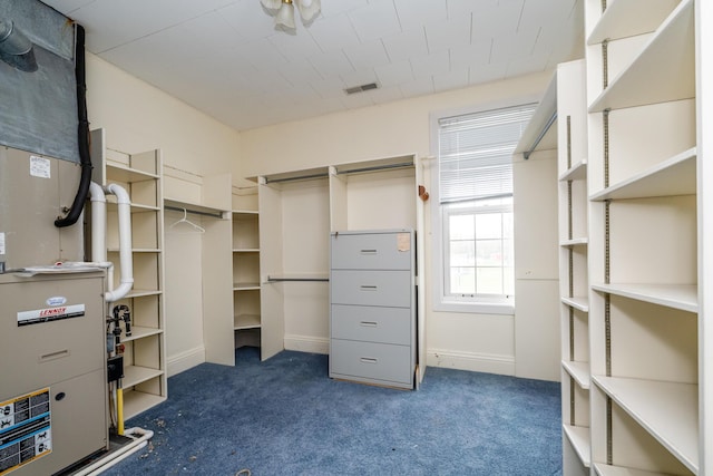 walk in closet featuring dark colored carpet, heating unit, and visible vents