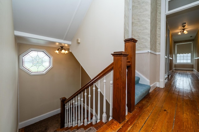 staircase featuring baseboards, a chandelier, and hardwood / wood-style flooring