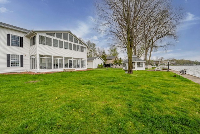 rear view of property with a yard, a sunroom, and a water view