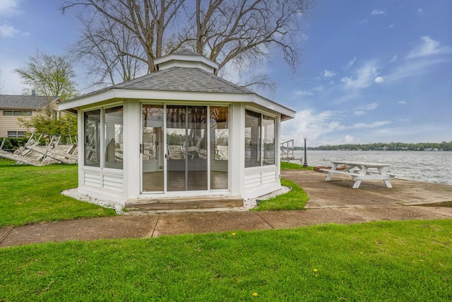 view of outdoor structure with a sunroom and a water view