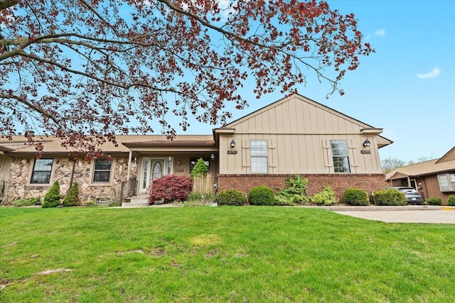 single story home featuring board and batten siding, stone siding, brick siding, and a front yard