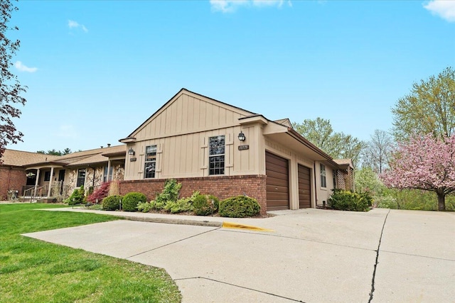 view of front of property featuring board and batten siding, brick siding, a garage, concrete driveway, and a front lawn