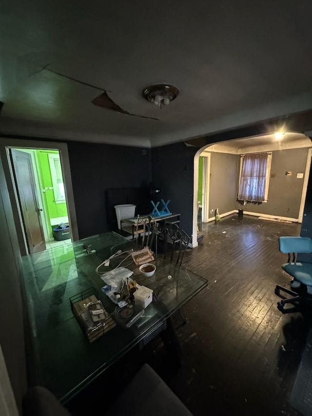 dining area featuring wood-type flooring, arched walkways, and baseboards