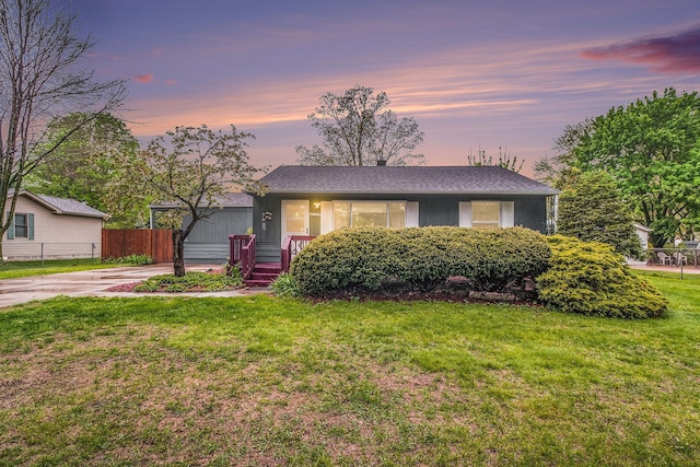 view of front of property with a lawn, driveway, and fence