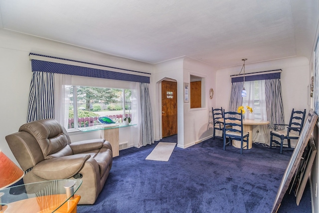 living room featuring dark colored carpet, visible vents, a healthy amount of sunlight, and arched walkways