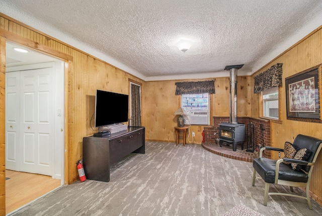 living area with a wood stove, a textured ceiling, wooden walls, and wood finished floors
