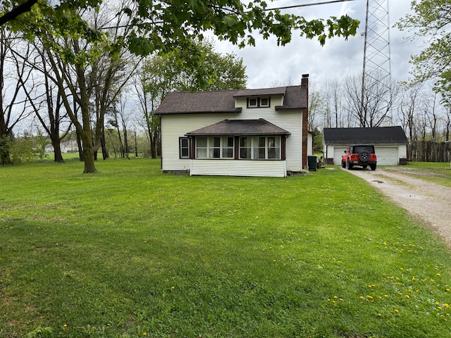 view of front of house featuring a chimney, an outbuilding, a detached garage, a front lawn, and roof with shingles