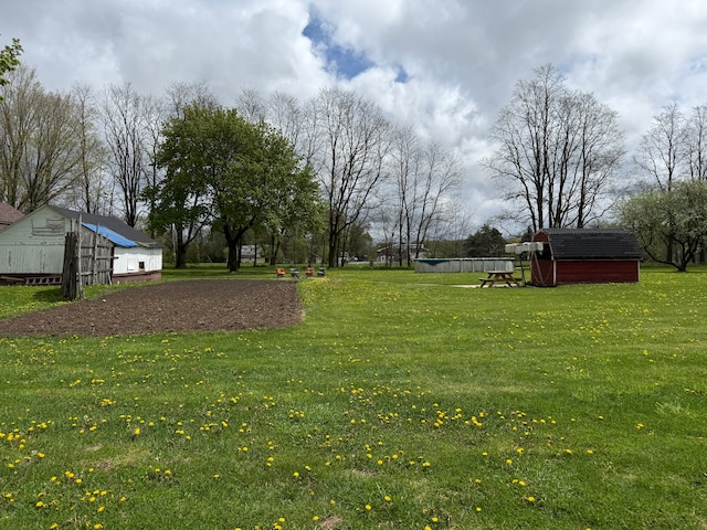 view of green lawn featuring a shed and an outbuilding