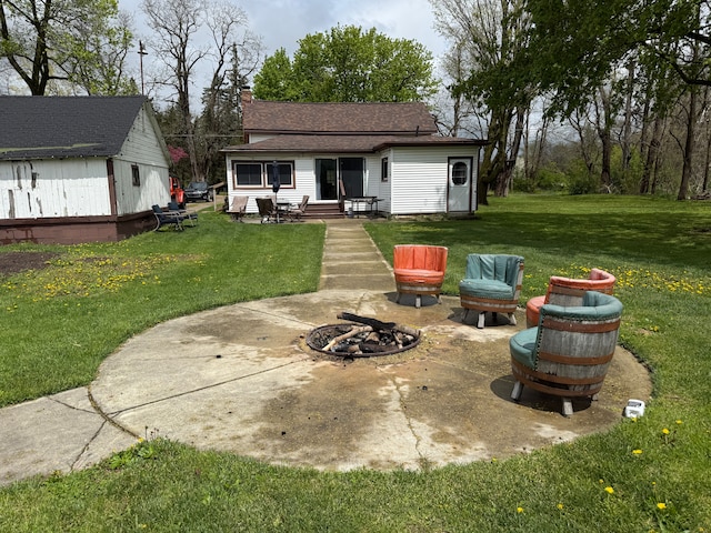 back of house with a fire pit, a patio, entry steps, a yard, and roof with shingles