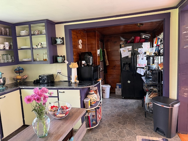 interior space featuring black fridge, dark countertops, and glass insert cabinets