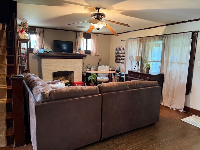 living room featuring a fireplace, ceiling fan, dark wood-style flooring, crown molding, and baseboards