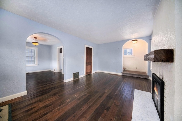 1009 S Webster St, Jackson, MI 49203 - unfurnished living room with arched walkways, wood-type flooring, a textured ceiling, healthy amount of natural light, and a textured wall