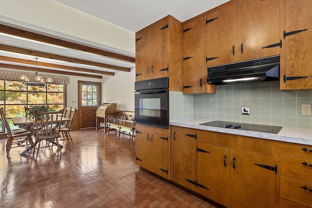 kitchen featuring brown cabinets, black appliances, under cabinet range hood, light countertops, and decorative backsplash