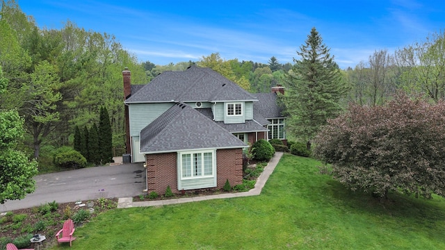 5401 Lone Pine Ct, Brighton, MI 48116 - back of house with a chimney, brick siding, a shingled roof, a lawn, and a wooded view