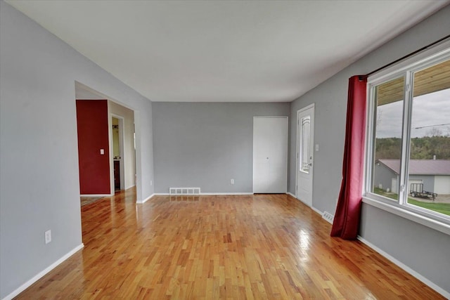 empty room featuring light wood-style flooring, baseboards, and visible vents