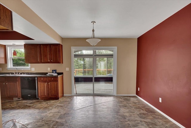 kitchen with dark countertops, black dishwasher, baseboards, and a sink