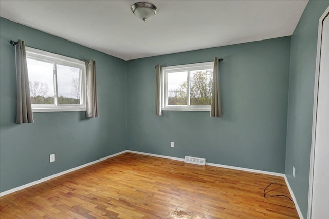unfurnished room with baseboards, visible vents, and wood finished floors