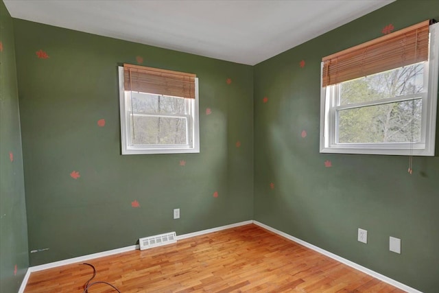 empty room featuring baseboards, visible vents, and wood finished floors