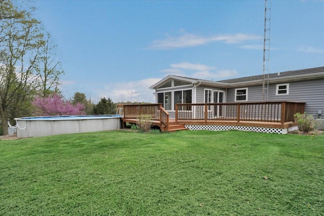 rear view of house with a yard, a deck, and an outdoor pool