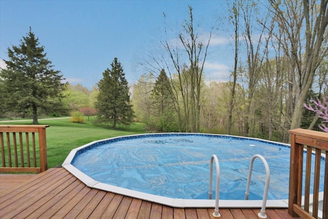 outdoor pool featuring a wooden deck and a lawn