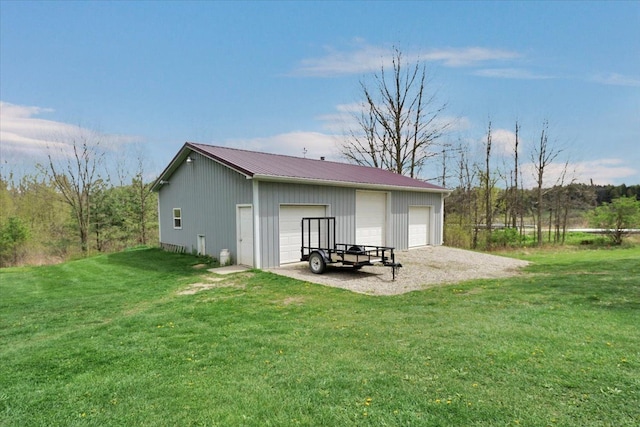 rear view of property featuring a garage, a lawn, metal roof, board and batten siding, and an outdoor structure