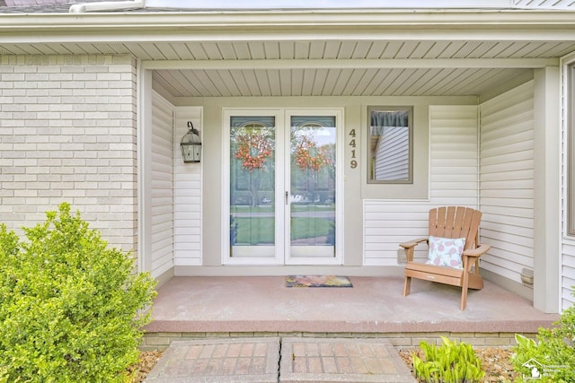 property entrance with a porch and brick siding