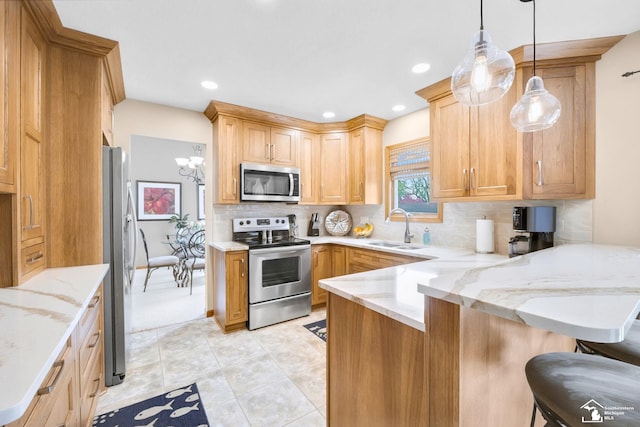 kitchen with light stone countertops, a sink, a peninsula, stainless steel appliances, and tasteful backsplash