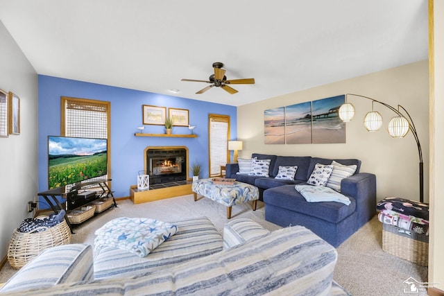 living area with carpet floors, a ceiling fan, a glass covered fireplace, and baseboards