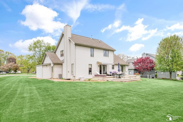 back of property with a chimney, central AC unit, and a lawn