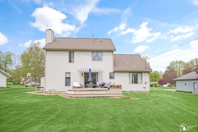 rear view of house featuring a shingled roof, a yard, a chimney, and a deck