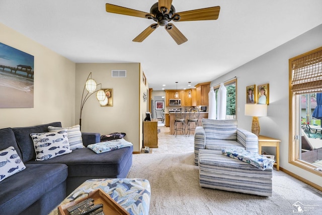 living area with light colored carpet, a ceiling fan, and baseboards