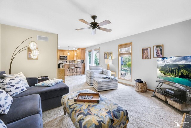 living room with light colored carpet, a ceiling fan, and baseboards