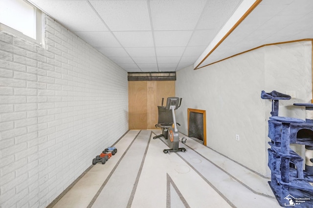 workout room with brick wall and a paneled ceiling