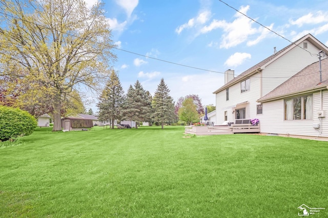 view of grassy yard with a wooden deck