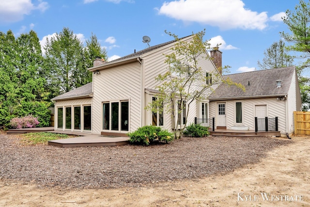 rear view of property featuring fence, a chimney, and a deck