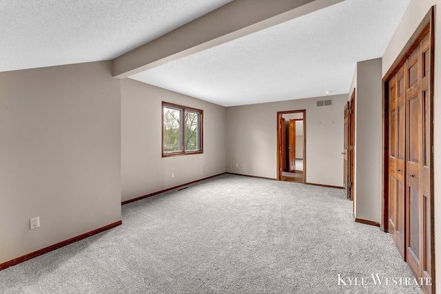 spare room with light colored carpet, a textured ceiling, visible vents, and baseboards