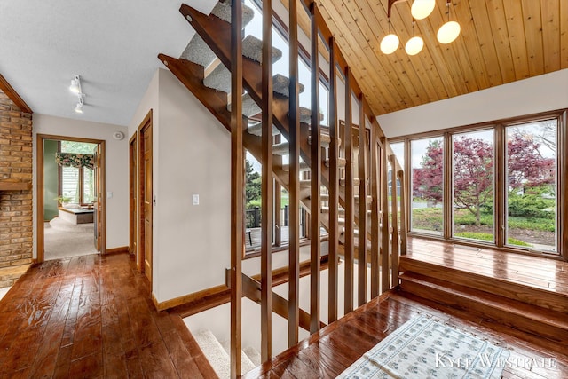 stairway featuring baseboards, rail lighting, and hardwood / wood-style flooring