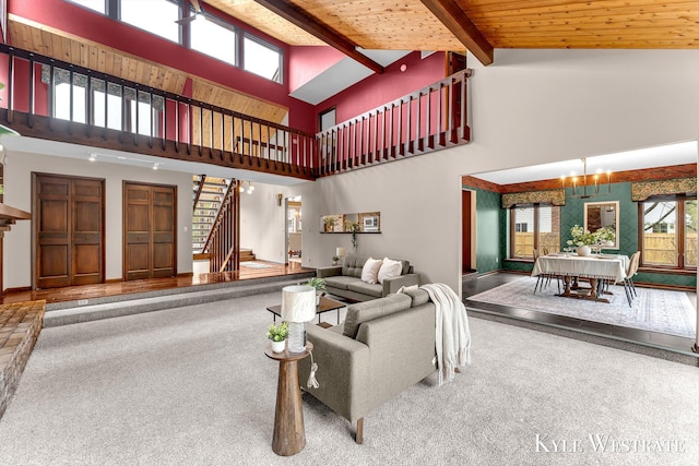 carpeted living area featuring a notable chandelier, plenty of natural light, stairway, and high vaulted ceiling