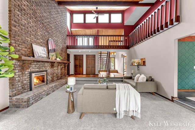 living room featuring a fireplace, carpet floors, a ceiling fan, a high ceiling, and baseboards