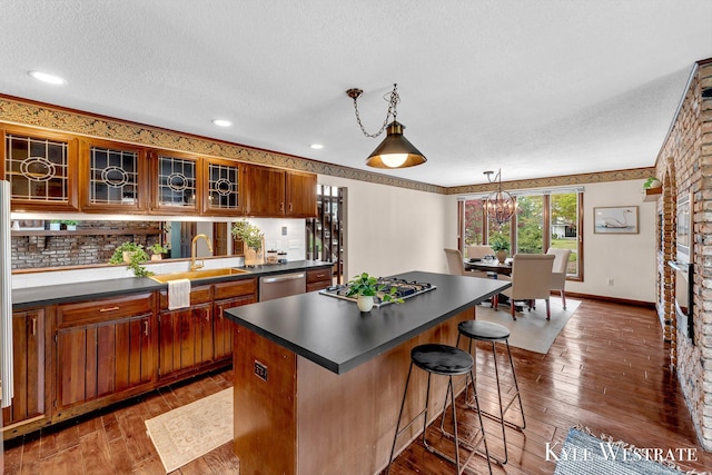 kitchen with dark wood-style floors, dark countertops, a sink, and a kitchen island