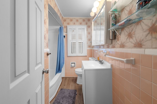 full bathroom with tile walls, wood finished floors, vanity, toilet, and wallpapered walls