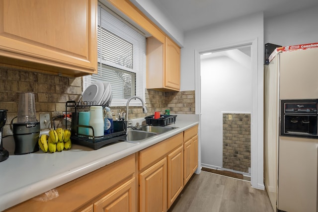 kitchen with white fridge with ice dispenser, a sink, light wood-style floors, light countertops, and tasteful backsplash