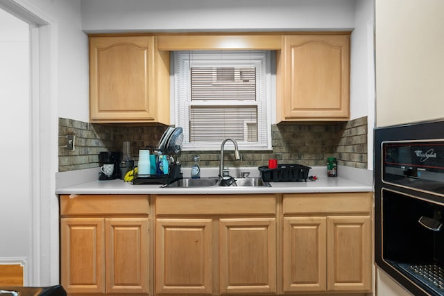 kitchen featuring a sink, decorative backsplash, light countertops, and light brown cabinetry