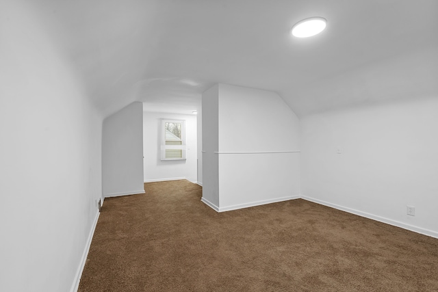 bonus room with lofted ceiling, dark carpet, and baseboards