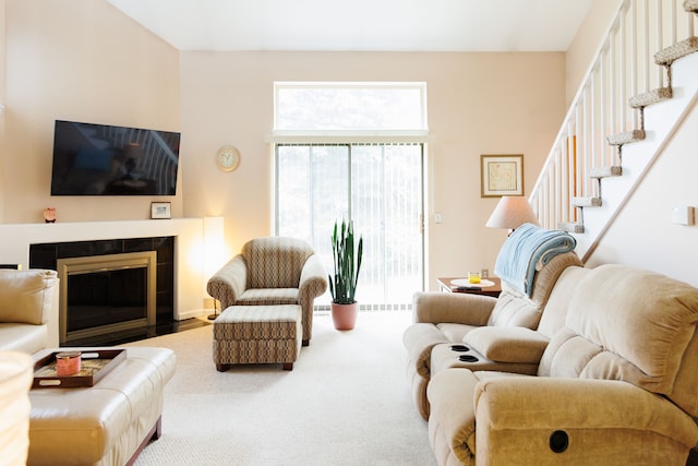living area with stairway, carpet floors, and a tiled fireplace