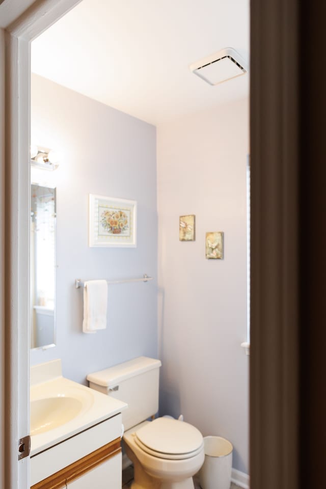 half bathroom featuring toilet, visible vents, and vanity