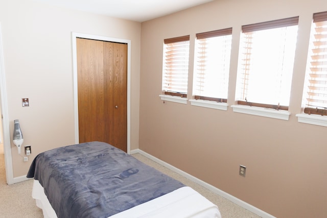 carpeted bedroom with baseboards, multiple windows, and a closet