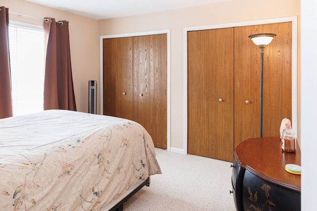 bedroom with light colored carpet and multiple closets