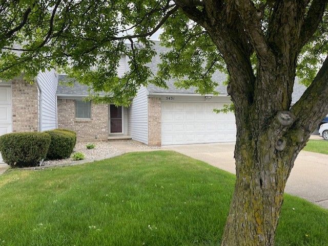 ranch-style house featuring concrete driveway, a garage, brick siding, and a front yard