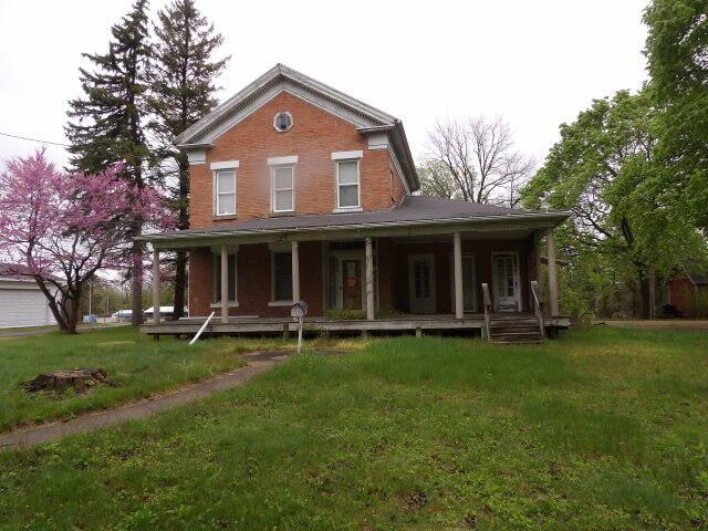 view of front of house featuring covered porch, a front lawn, and brick siding